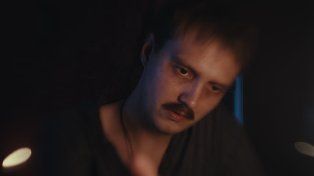 A man with a mustache in a dimly lit setting