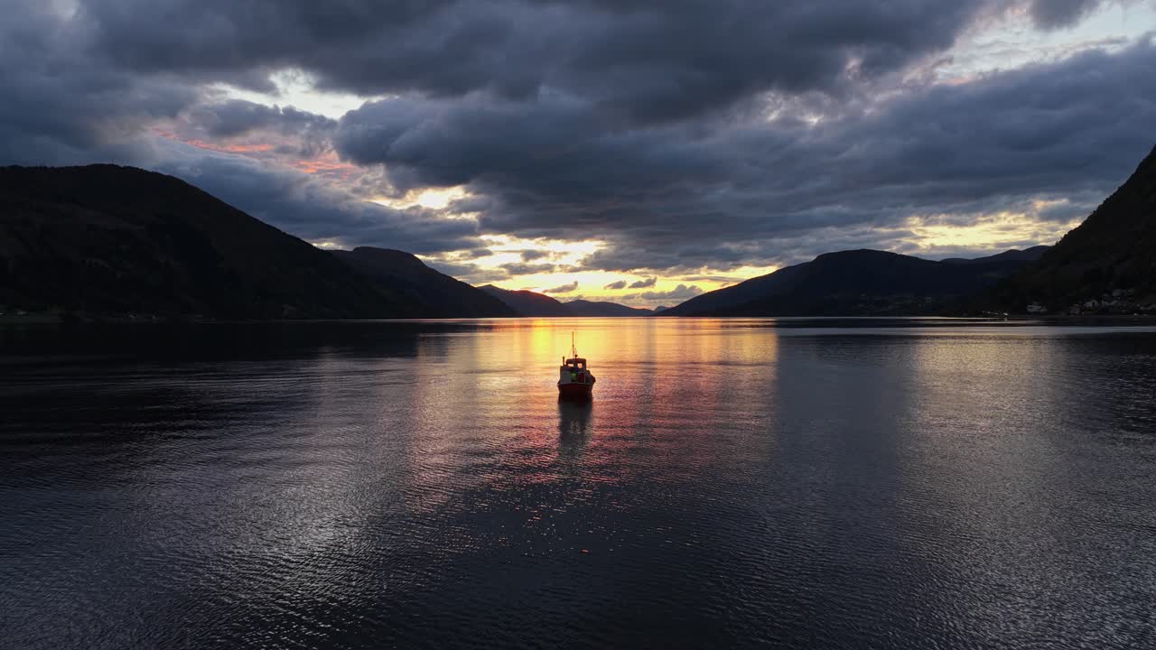 Luftaufnahme zur goldenen Stunde eines Fischerbootes, das durch den Nordfjord in Norwegen gleitet
