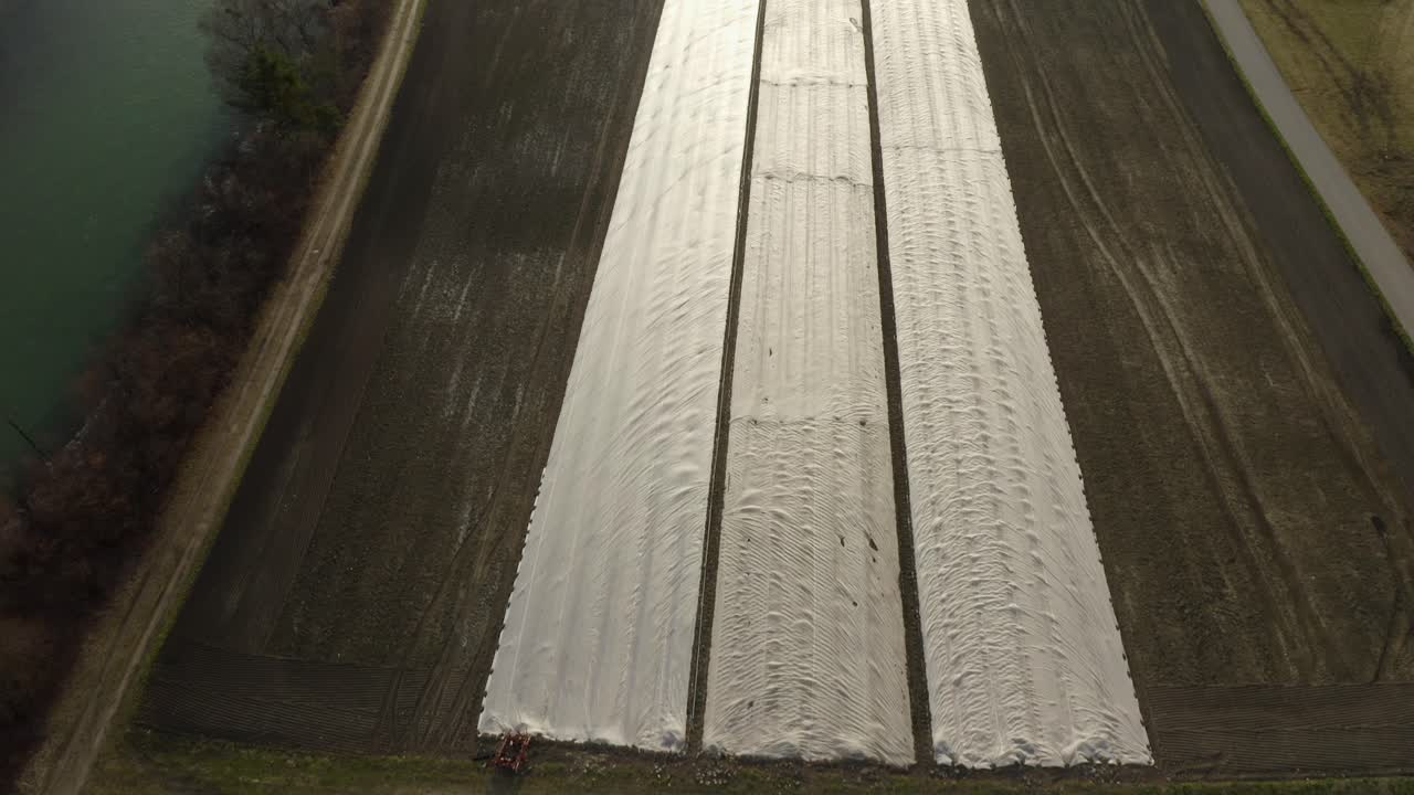 Drone view of farming rows with plastic covering in spring fields.