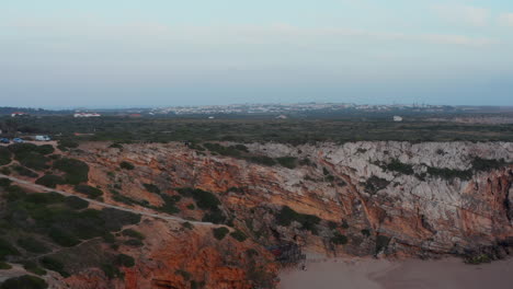 Malerische-Luftaufnahme-Des-Abgelegenen-Strandes-Versteckt-Zwischen-Felsigen-Bunten-Klippen-In-Lagos-Algarve,-Portugal,-Rückwärts,-Tag