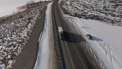 Aerial-shot-of-a-truck-pulling-a-trailer-on-a-mountain-road