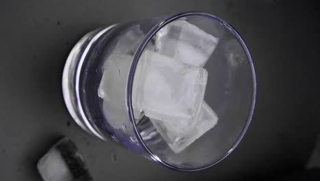 Static-Shot-of-Ice-Cubes-Falling-into-Glass-from-Above,-Vertical-Shot