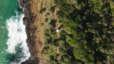 vista rotativa única de las olas que se estrellan contra una pared rocosa con un pequeño faro