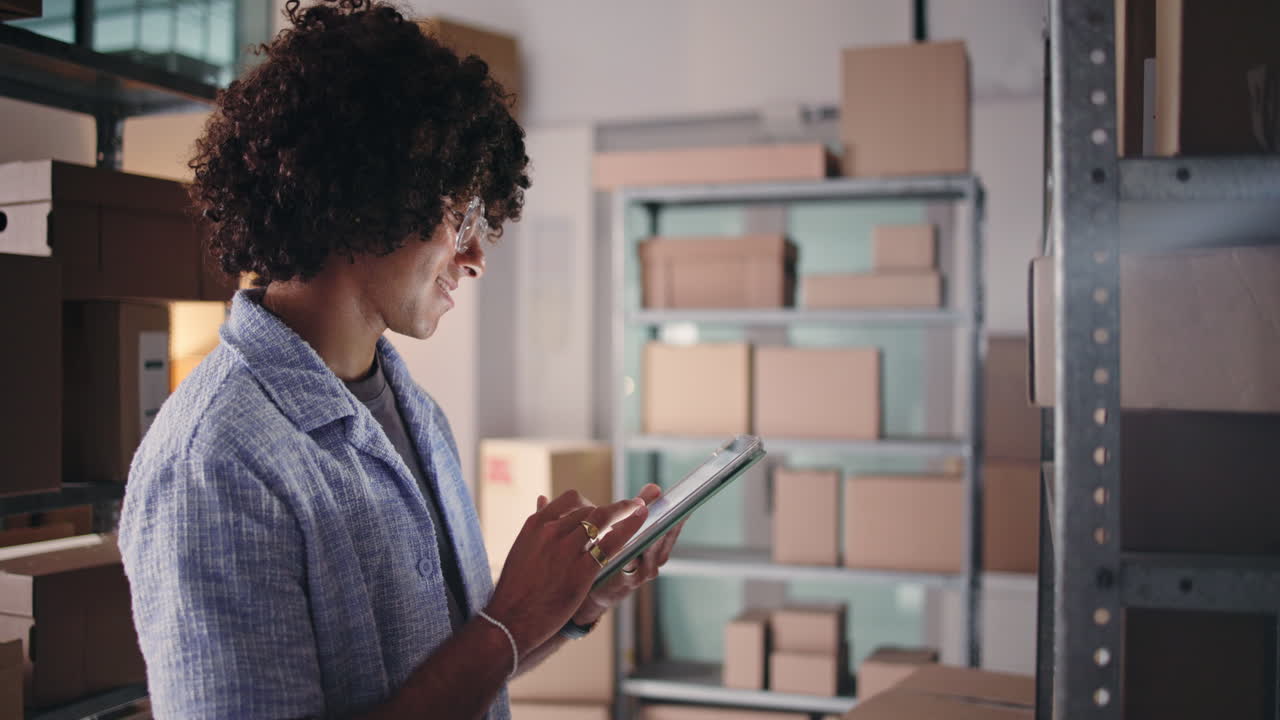 Happy Young Man Using Tablet to Manage Warehouse Inventory
