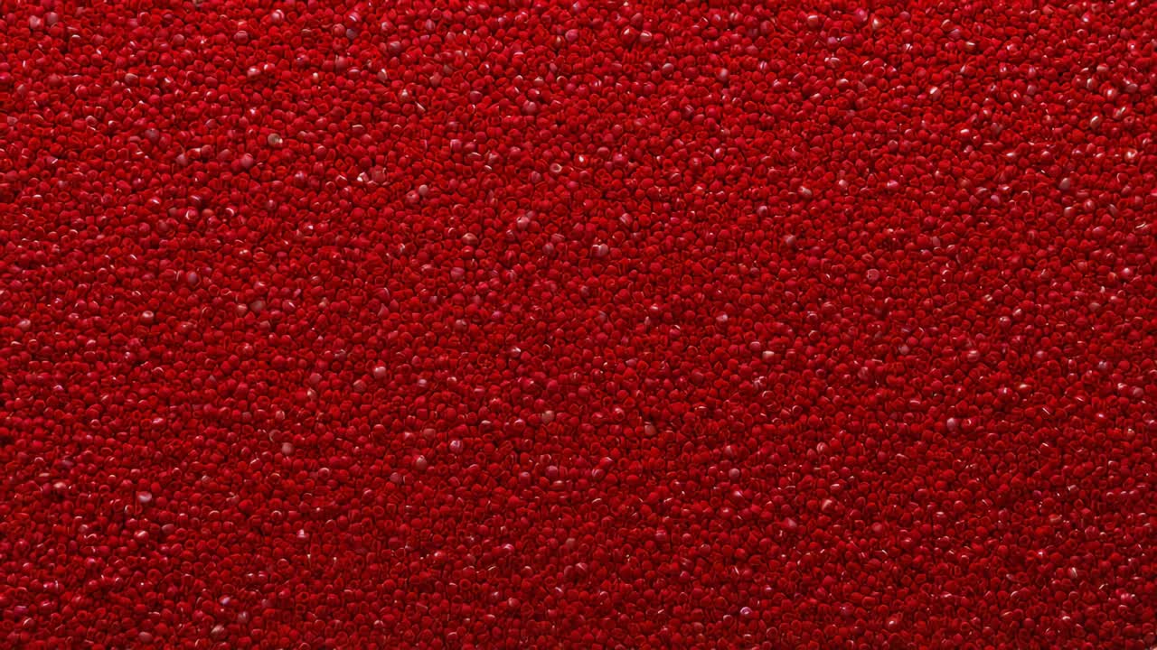 Recording macro camera adjusting focus while capturing red granulated surface in studio, highlights