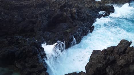 Una-Foto-De-Las-Olas-Rompiendo-En-Un-Pequeño-Acantilado-De-Roca-Volcánica-Negra