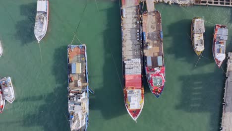 aerial top down of several ships with container,goods and cargo shipment at harbor during sunlight