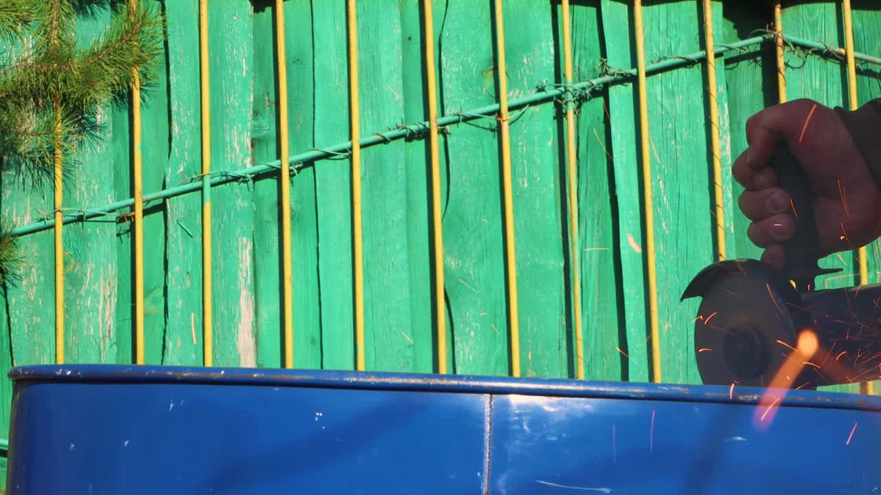 글 그라이더를 가진 남자 손이 파란색 금속 배럴을 잘라냈습니다.