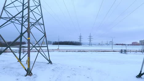 Drohnenblick-Auf-Elektrische-Türme,-Die-In-Einem-Winterfeld-Stehen.-Strommasten