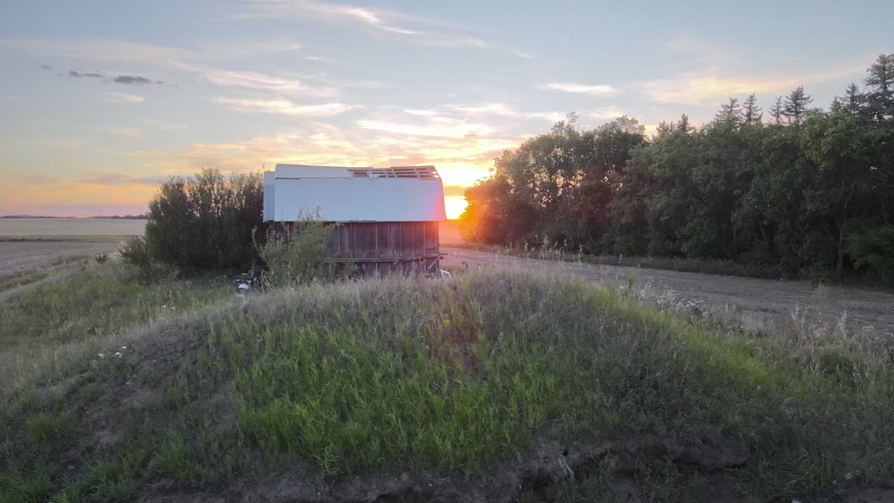 Tramonto colorato rivelato dietro una foresta e fienili abbandonati nell'Alberta meridionale