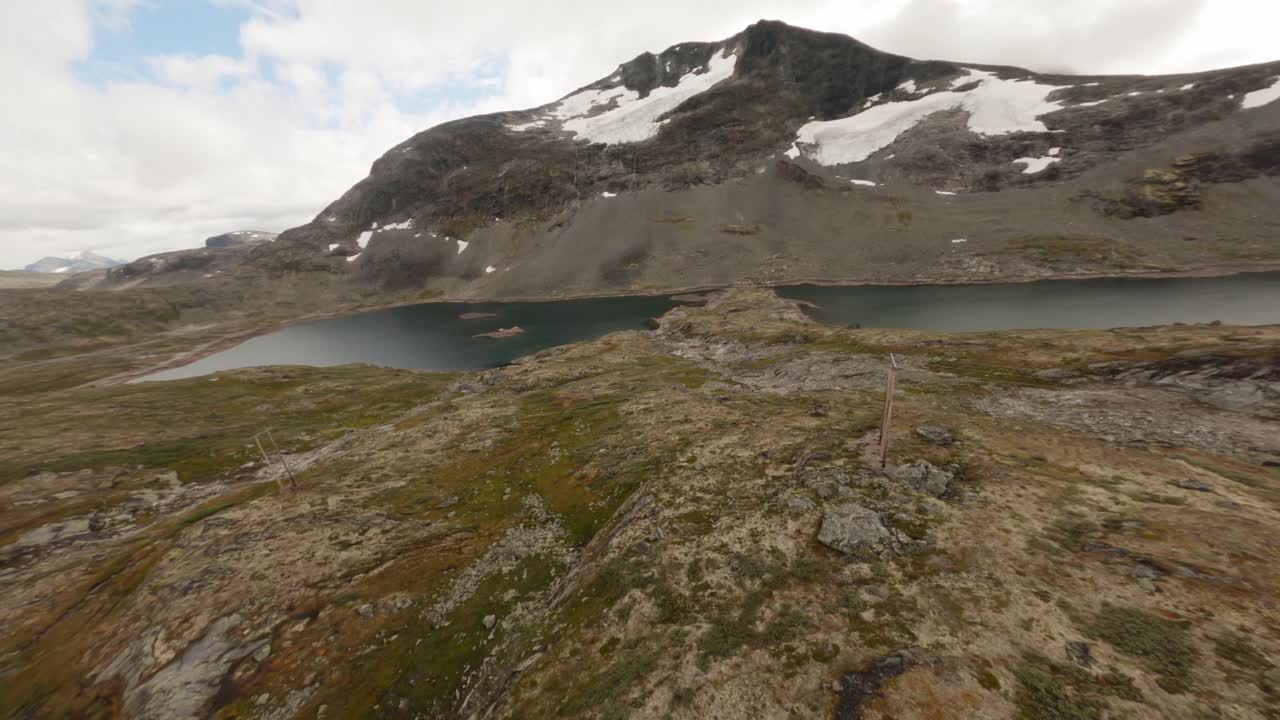 Remote mountain lake with rocky terrain and snow patches in Norway, peaceful mood