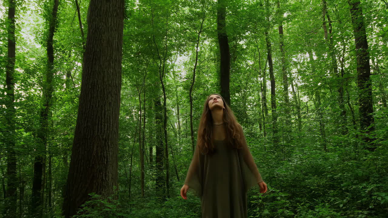 Woman in a lush green forest looking upwards