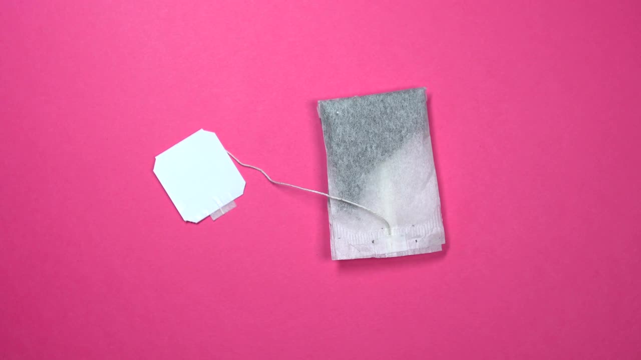 Tea bag with white label fast spinning on a rotating pink background.