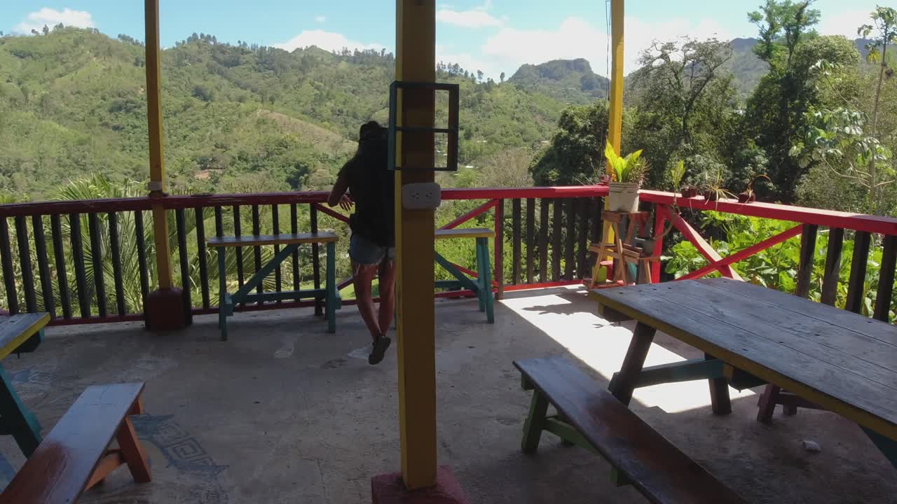 latina con mochila camina hasta el balcón en el albergue de la selva de montaña