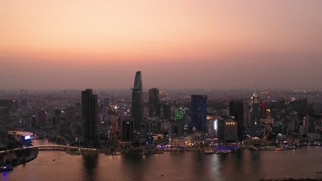 ciudad ho chi minh, horizonte icónico de vietnam y panorama aéreo frente al río saigon en una noche ocupada con edificios clave iluminados contra un hermoso cielo coloreado y reflejados en el río