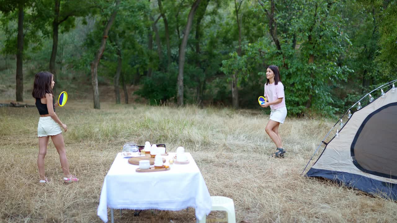 어머니 와 딸 이 캠핑 여행 에서 프리스비 를 연주 하고 있다