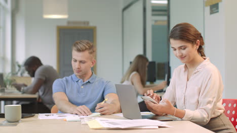 Lächelndes-Mädchen,-Das-Im-Coworking-Space-Eine-Nachricht-Auf-Dem-Mobiltelefon-Sendet