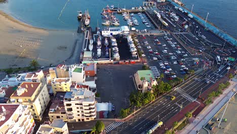 busy cargo port near seaside beach in los cristianos tenerife, aerial establish shot, canary islands