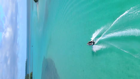 seguimiento aéreo de una lancha a motor que navega entre islas en la isla de los pinos, nueva caledonia - video vertical