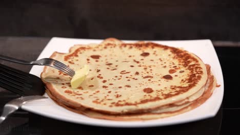 pancakes on a plate and grease with butter. big pancake. cooking smoke goes up from pancake. big pancakes with holes. pancake weekend. russian tradition. slow motion video