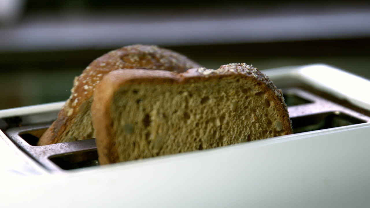 dos rebanadas de tostadas saliendo de la tostadora en la cocina