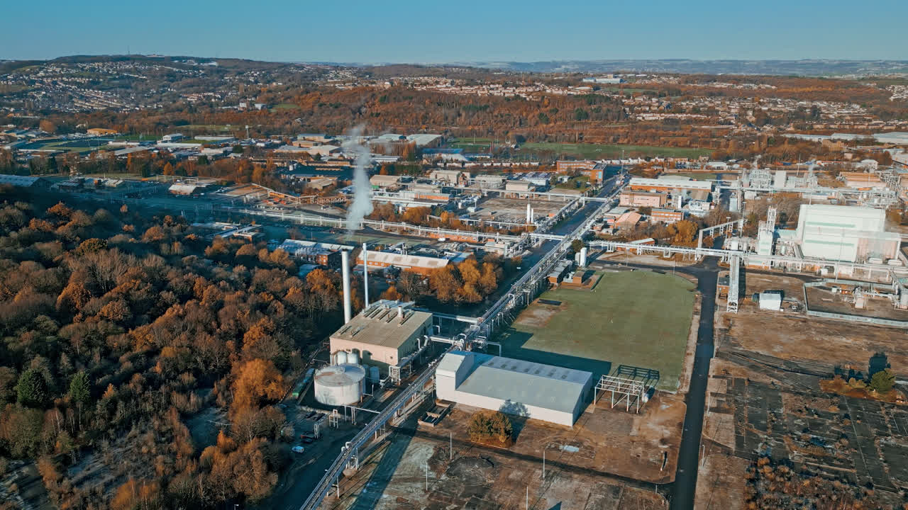 imágenes aéreas que avanzan hacia una gran planta química industrial, que muestran tuberías, estructuras metálicas, torres de refrigeración y almacenamiento de productos químicos