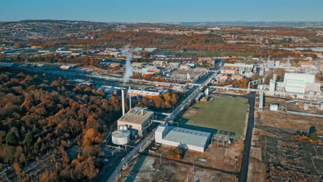 aerial footage moving towards a large industrial chemical plant, showing pipelines, metal structures, cooling towers and chemical storage