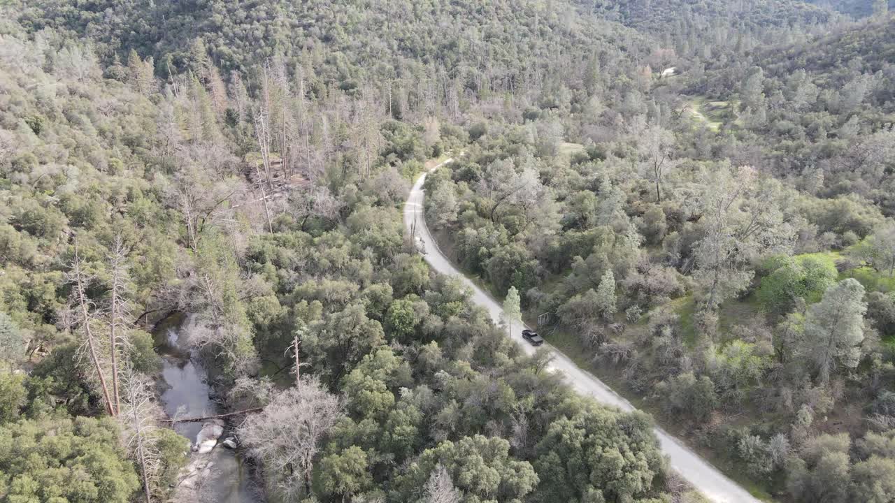 camioneta conduciendo junto a un río en las montañas en un camino de tierra