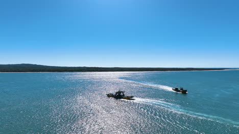 Flight over the azure waters of the Great Sandy Strait separating mainland Australia from Fraser K&#039;gari Island. Flying above two low slung car ferries sailing past each other on a spectacular day