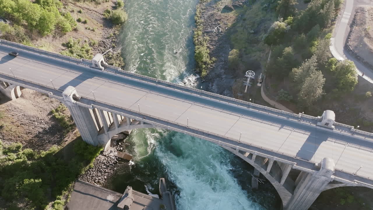 A bridge crosses over a fast-moving river in Spokane. The water swirls below with strong current
