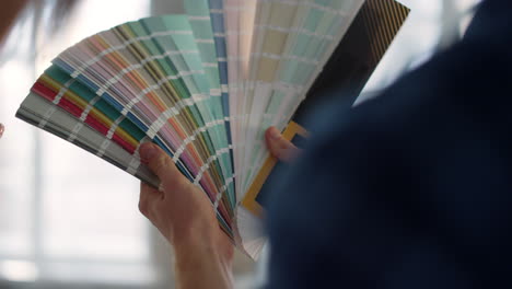 unknown couple choosing color for walls on swatches book on blurred background.