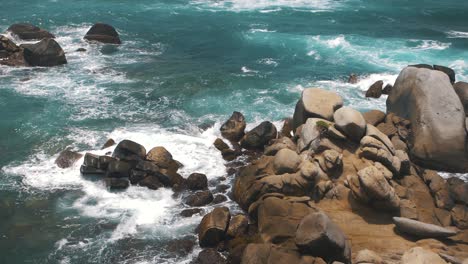 waves crashing against a stack of rocks on a cliff in slow-motion in tayrona park, colombia