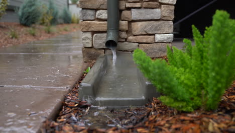 close up view of a downspout with water flowing on a rainy day