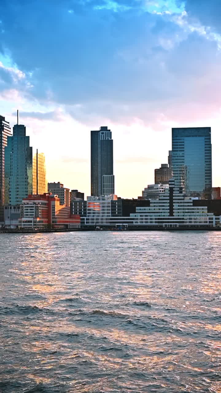 Arranha-céus no horizonte de Nova York ao pôr do sol. Observando os edifícios à beira-mar da metrópole do rio. Vídeo vertical
