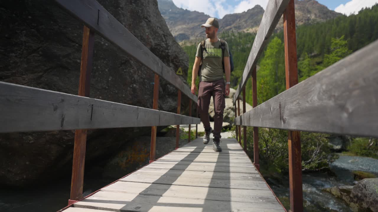 ángulo bajo: hombre en puente de madera con fondo de montaña