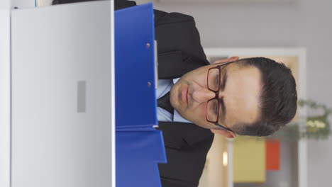 Vertical-video-of-Home-office-worker-man-reviewing-paperwork-files.