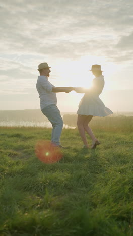 dos pájaros enamorados giran amorosamente en una colina cubierta de hierba al atardecer, al lado de un lago sereno. el hombre, vestido con una camisa blanca, sombrero y vaqueros, abraza a su esposa, que lleva un vestido blanco fluido