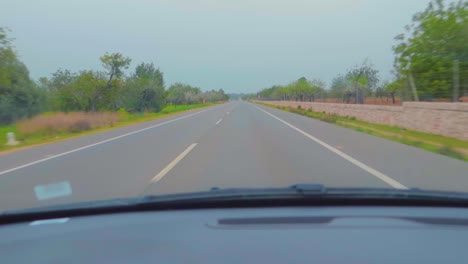 A-fast-straight-drive-on-a-highway-from-the-lush-green-environment,-captured-from-the-car-windscreen