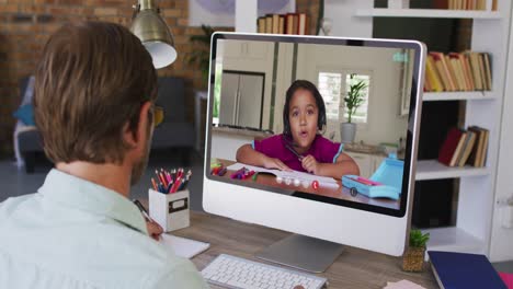 Caucasian-male-teacher-taking-notes-while-having-a-video-call-with-african-american-boy-on-computer