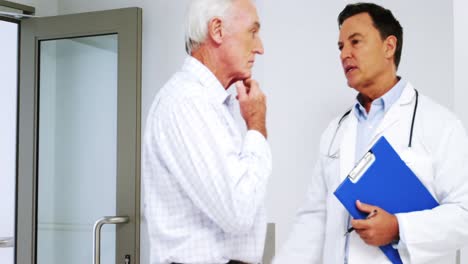 Male-doctor-interacting-with-male-senior-man-in-the-passageway