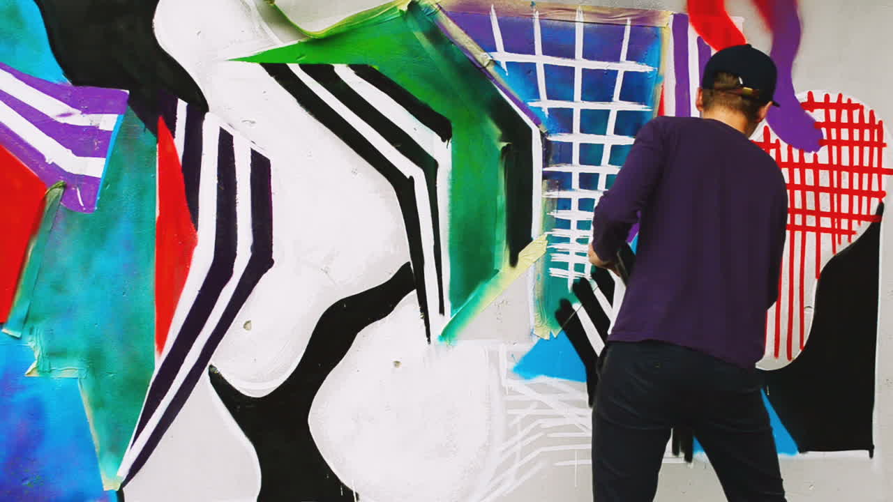 Kunstneren tegner graffiti på et hegn. Abstrakt tegning