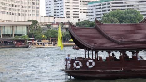 a traditional boat moves across a river in a city.