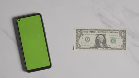 overhead currency shot of us 1 dollar bill next to green screen mobile phone