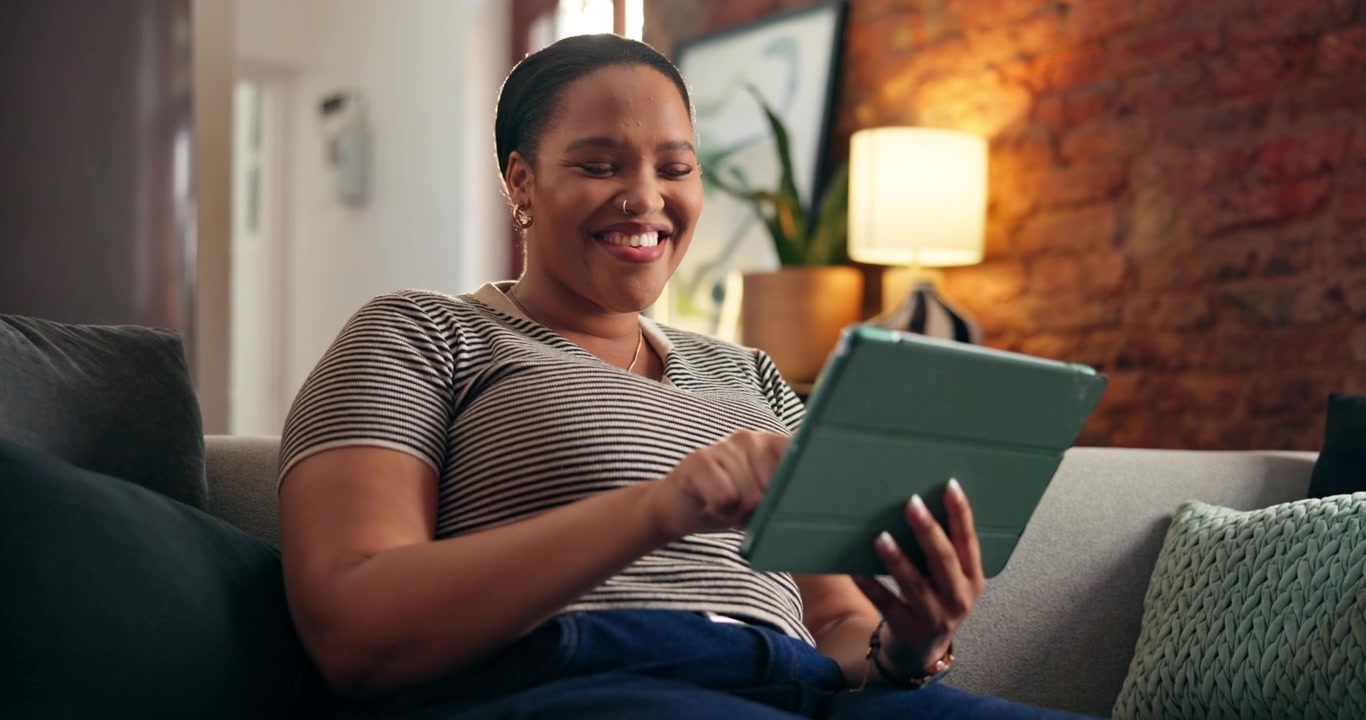 Happy Woman Using Tablet on Sofa in Living Room