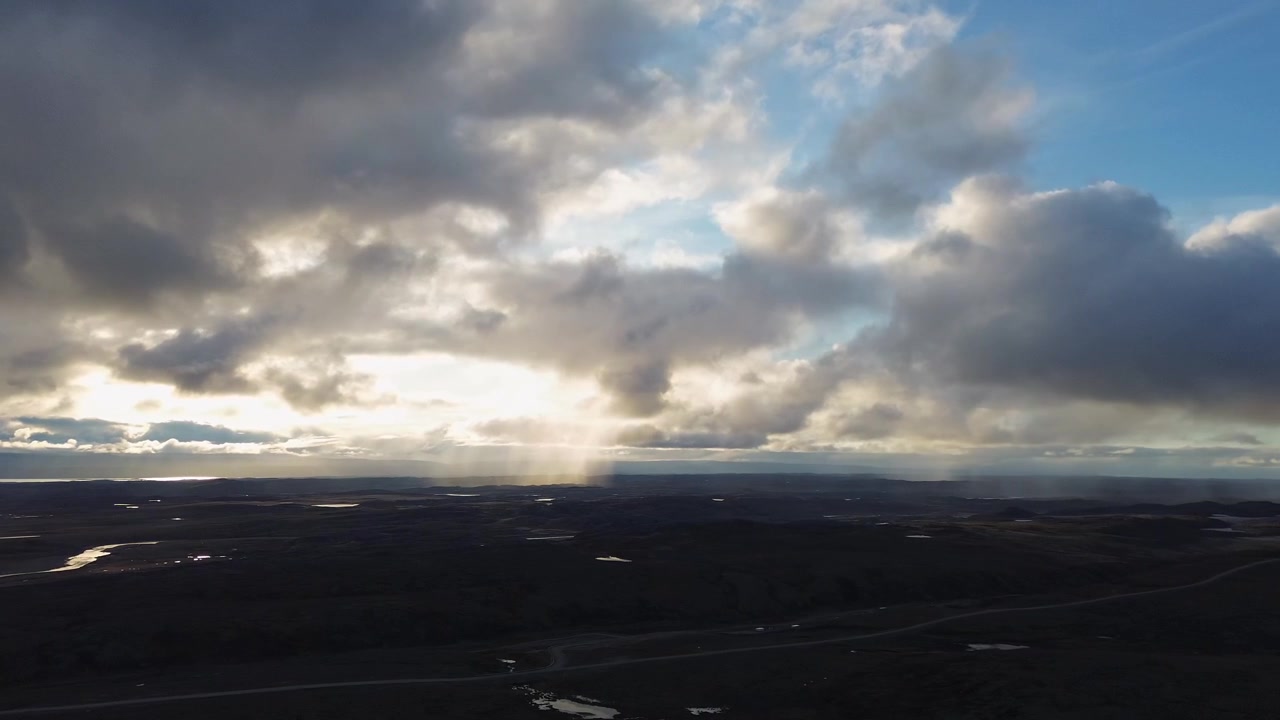 High elevation drone view showing dramatic cloud formations and rain shafts over open tundra terrain near Iqaluit
