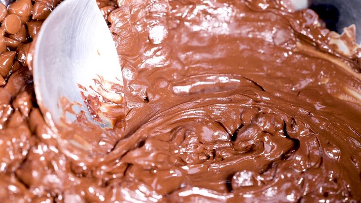 Spoon stirring melting chocolate chips in a pan