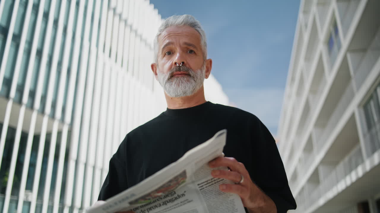 Successful senior reading newspaper on street closeup. Handsome grey bearded man