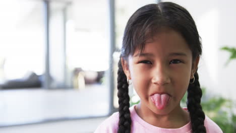 chica biracial con cabello oscuro en trenzas saca su lengua juguetón, con espacio de copia