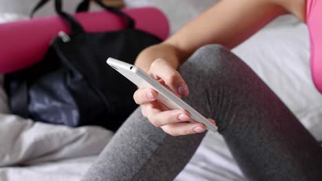 female athlete using mobile phone in bed