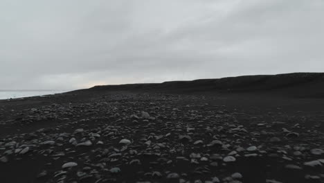 rocks and black volcanic sand beach on coast of iceland, aerial view, low angle